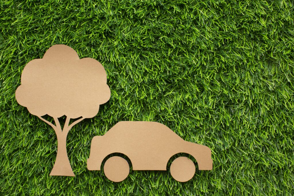 arbre et voiture en carton sur pelouse symbolisant un des avantages de l'autopartage : la mobilité durable